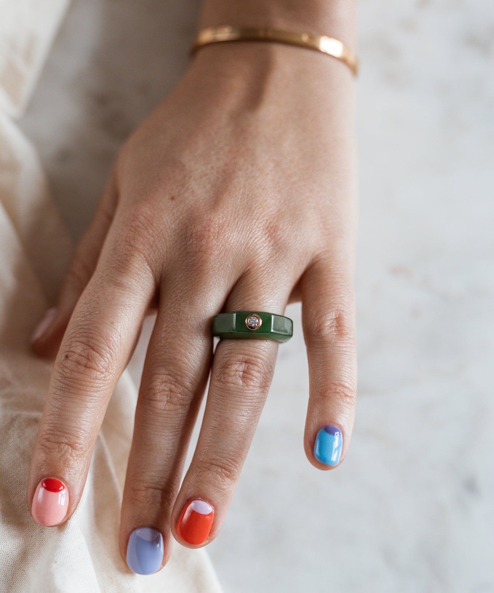 A woman wearing colorful nails and a WALD Berlin Shining Star Fine Jewelry Jade Ring.