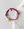 The Smilie Dude Red Friendship Bracelet by WALD Berlin, featuring a yellow smiley face charm, is displayed on a marble surface next to light-colored fabric.
