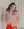 A person poses against a light background, wearing a fluffy pink jacket and red dress, beautifully highlighted by XL Pearl Heart I Am Love Earrings from WALD Berlin.