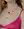 A person wearing a pink top, two heart-shaped necklaces, and WALD Berlin's XL Pearl Heart I Am Love Earrings with an XL sweet water pearl. Their curly hair complements their slightly visible smile.