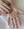 A person's hands displaying WALD Berlin Linda Earrings Gold, sterling silver earrings, and painted nails against a white fabric background.