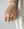 A close-up of a woman's hand resting on a marble surface, wearing a WALD Berlin Shining Star Gold Ring and bracelet.