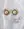 The Pop Soleil Earrings by WALD Berlin, featuring large pearl centers and spiked gold edges, are displayed alongside two 18k gold plated rings with single pearls on a white fabric background.