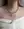 A person wears layered gold-plated brass necklaces, including the WALD Berlin Pop Dolphin Necklace, with an off-shoulder white gathered fabric top.