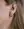 Close-up of a person’s ear with long blonde hair, wearing WALD Berlin's Pop Wave Earrings Small—an 18k gold plated creole hoop in the lobe and two small 925 silver pin studs in the upper ear.