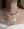 A woman layers WALD Berlin necklaces, featuring pastel beads and 18k gold-plated strands with two Pop Smilie Medallion Green pendants, over a white off-shoulder top for a fresh summer look.