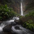 Stream leading towards Kapas Biru waterfall through a lush landscape