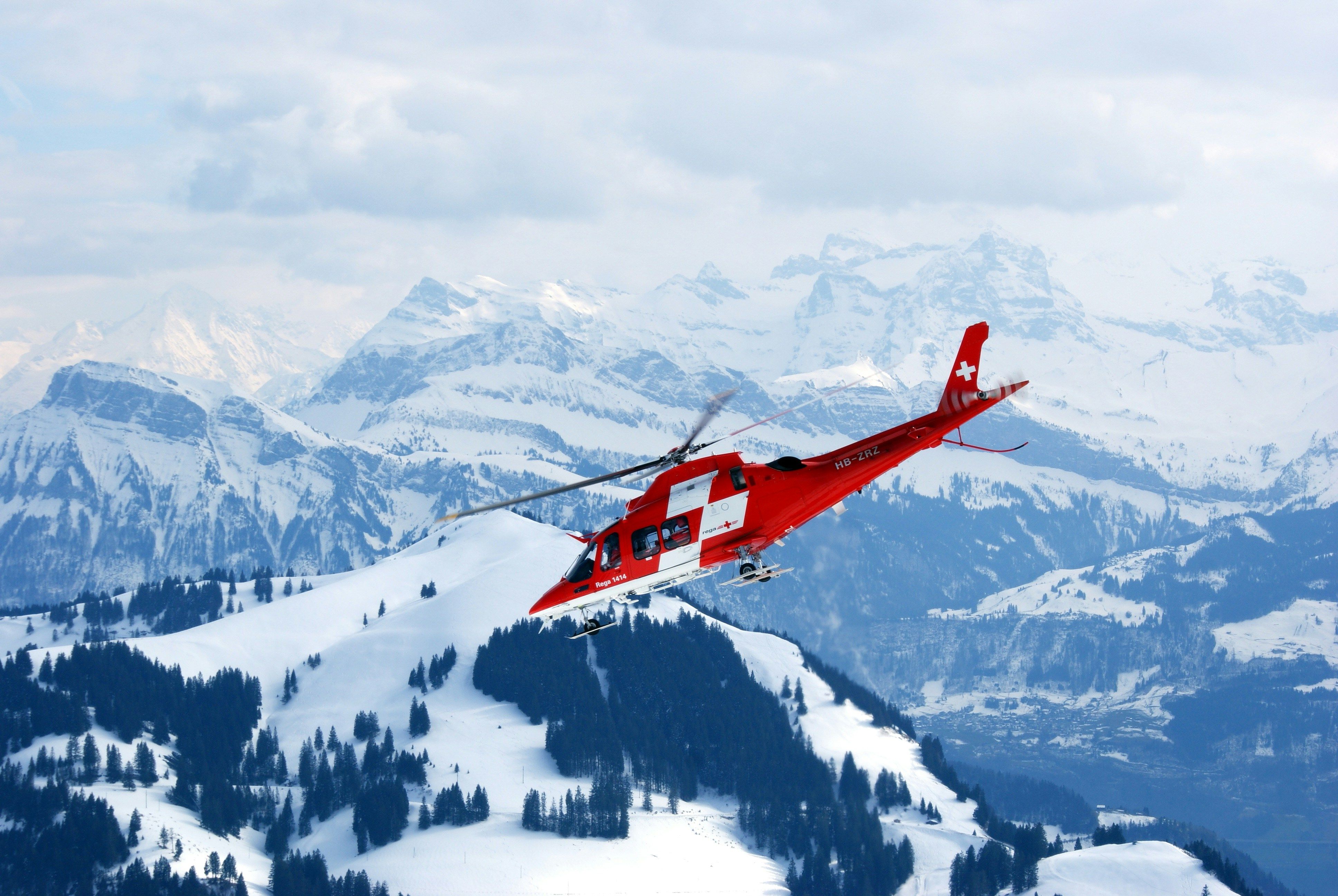 Red and white rescue helicopter in flight during snow