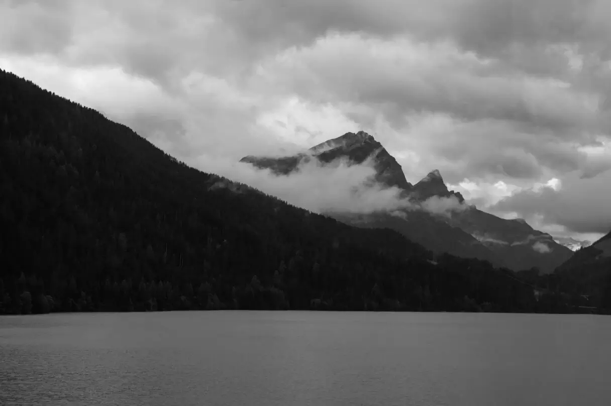 Scenic view of a mountain partially obscured by clouds reflecting on a lake.