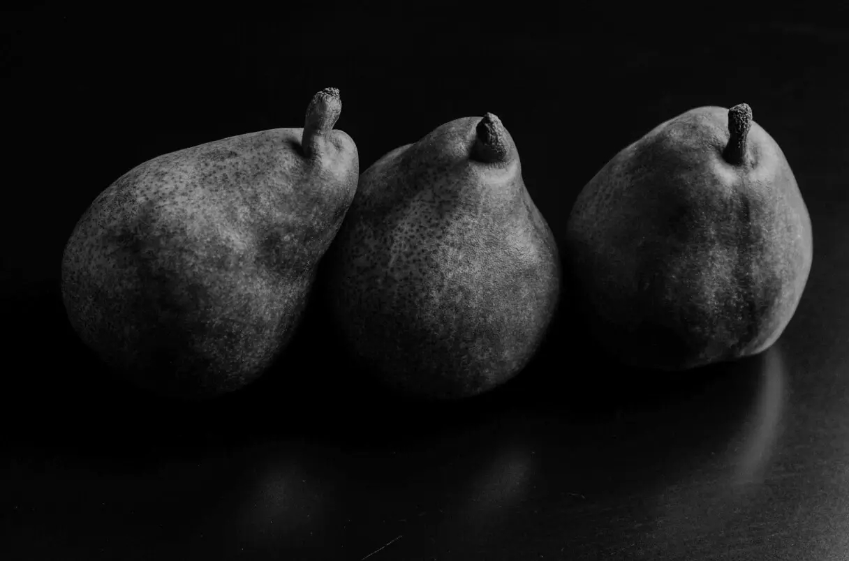 Three pears in a row against a dark background.