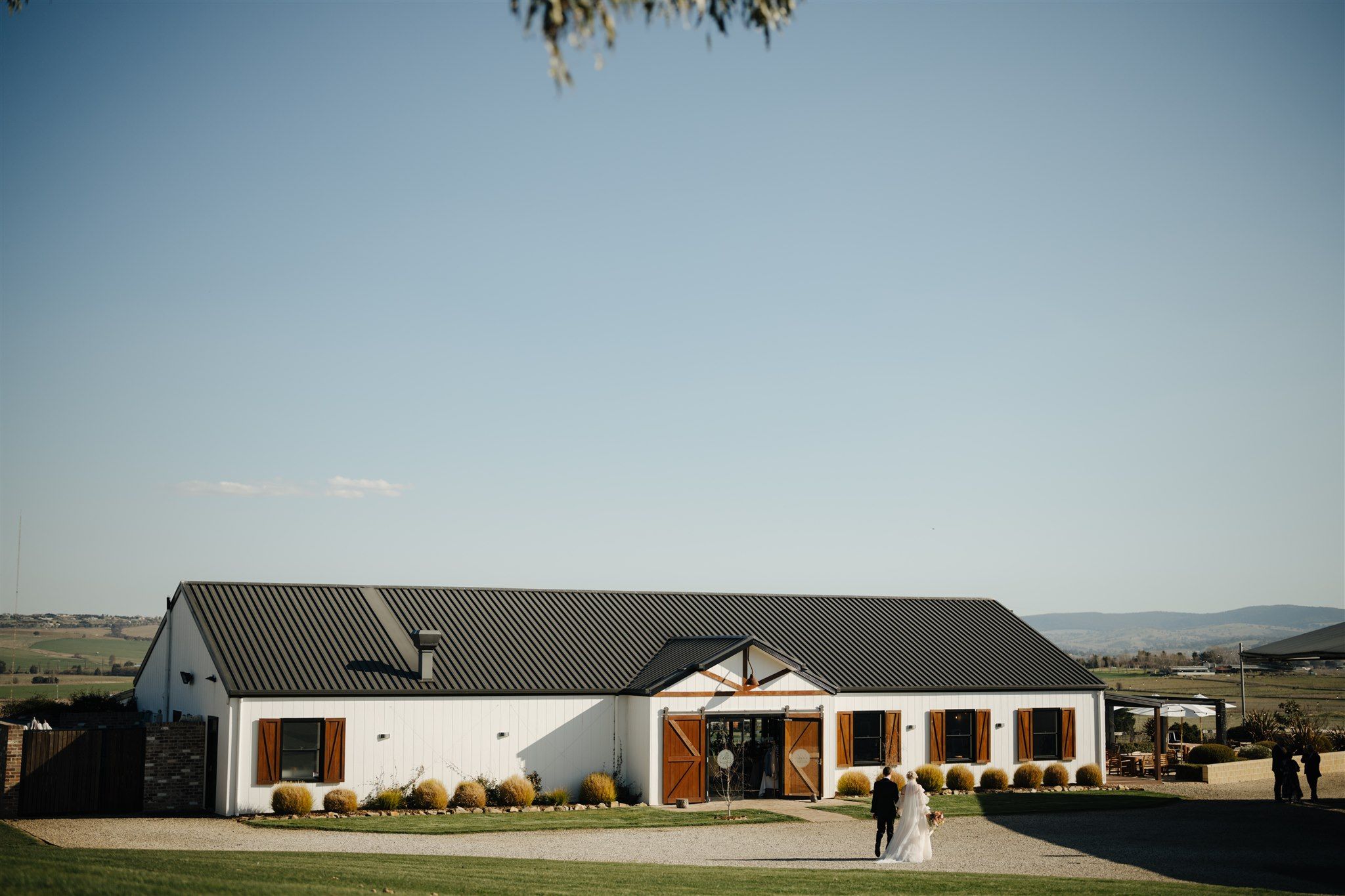 Bride and groom entering their wedding reception in the white barn at Boxgrove