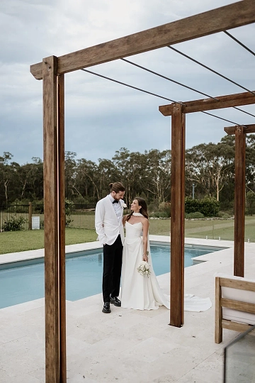 A couple has their photo taken beside the crystal blue pool at Saddle Ridge.