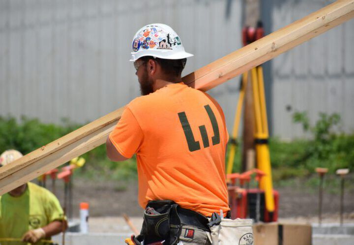 Weigand carpenter carrying lumber on a construction site