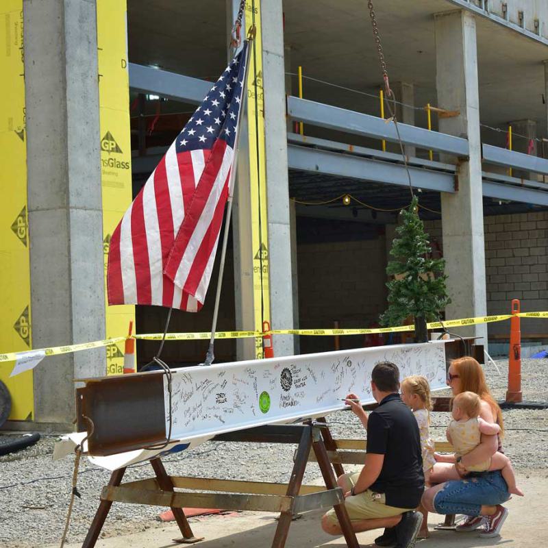 Family signing a steel beam at a Weigand Construction jobsite