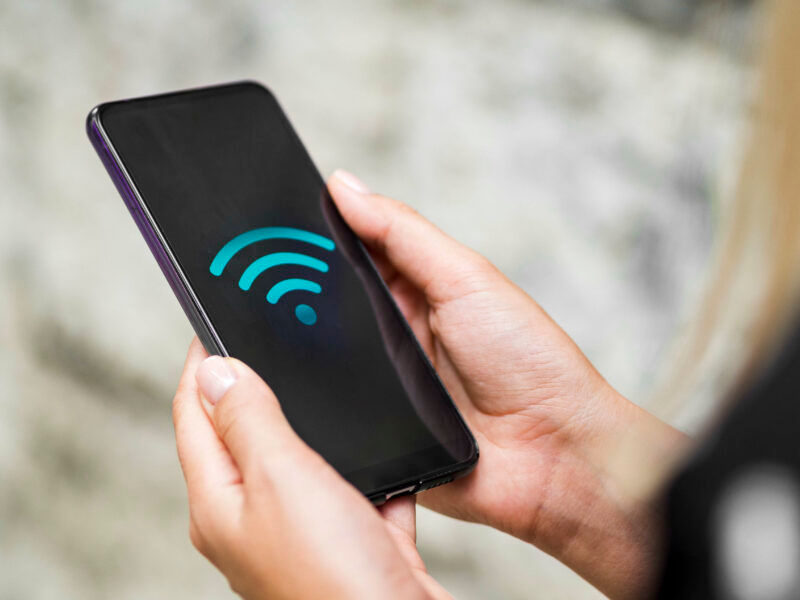 Mão feminina segurando um celular, utilizando wi-fi público