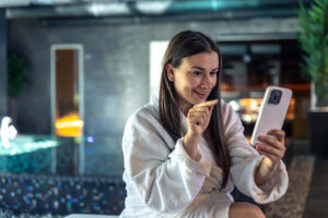 Uma mulher na faixa dos 30 anos está em um SPA utilizando o Wi-Fi gratuito, enquanto a empresa utiliza disso como estratégia de retenção de clientes.