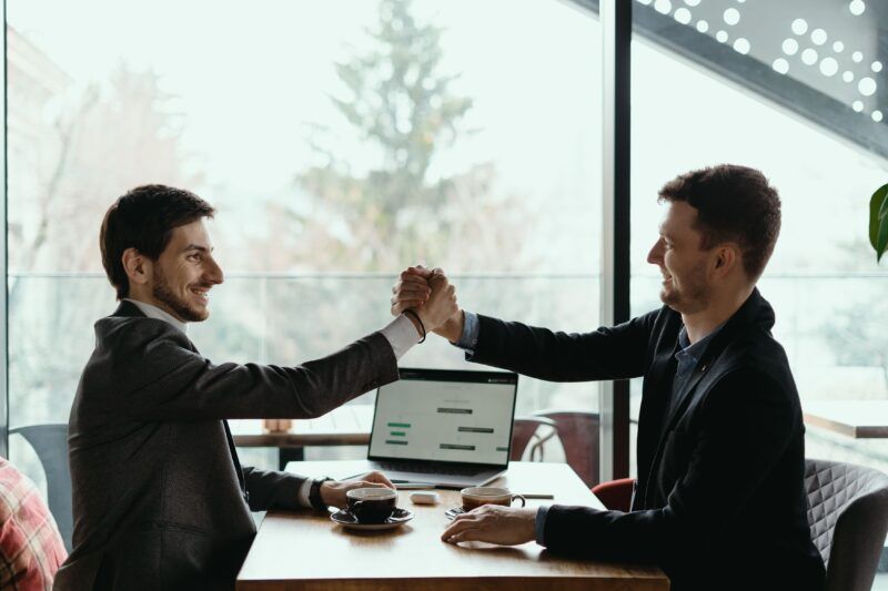 Dois homens usando terno estão em um escritório dando as mãos, representando o fechamento de uma parceria entre ISPs e WiFi Marketing