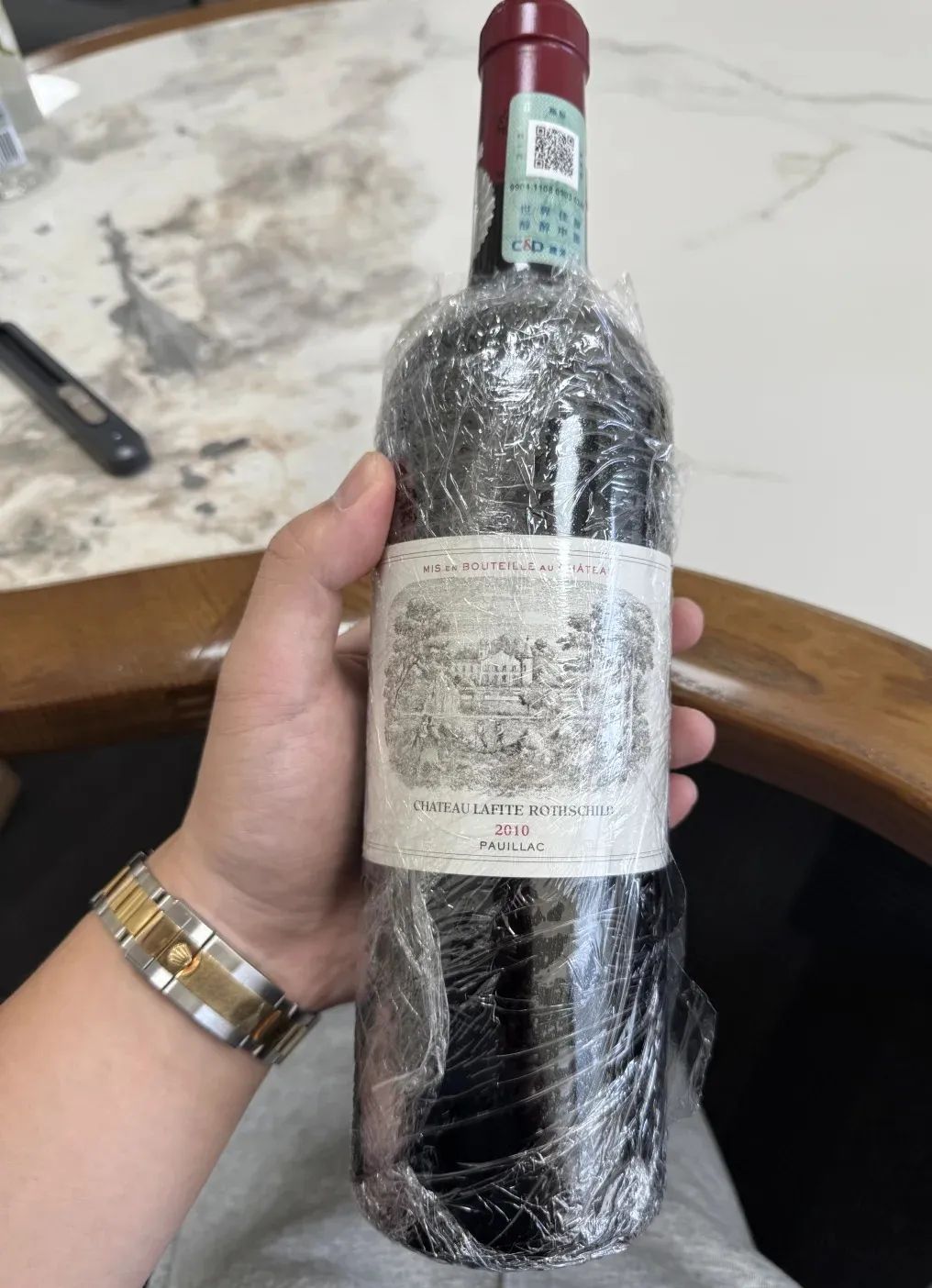 手持拉菲 Lafite 2018 紅酒,正標可見 CHATEAU LAFITE ROTHSCHILD 與 2018,酒液位於瓶頸