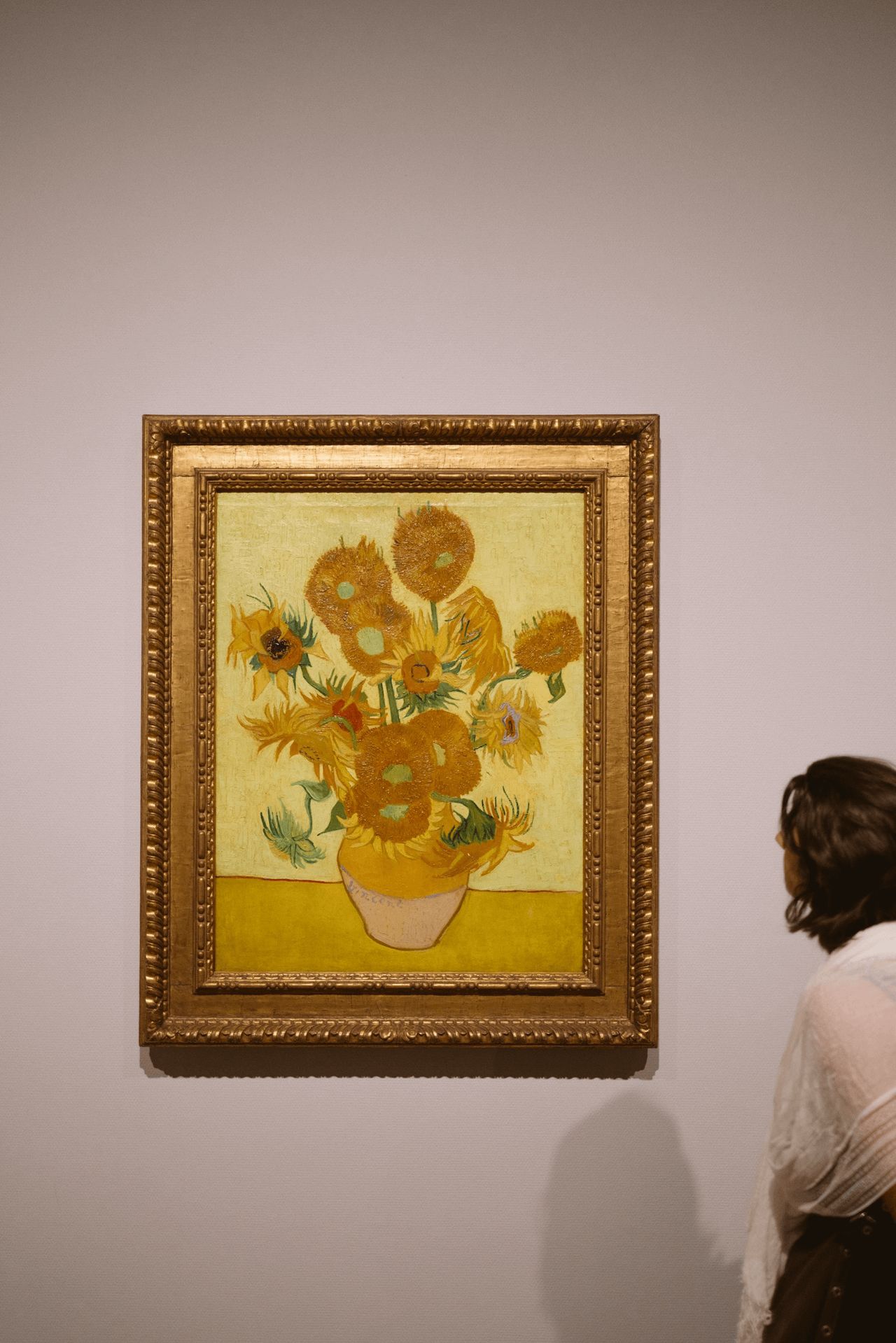 Woman looking at Van Gogh’s painting of sunflowers at his museum in Amsterdam ⌘