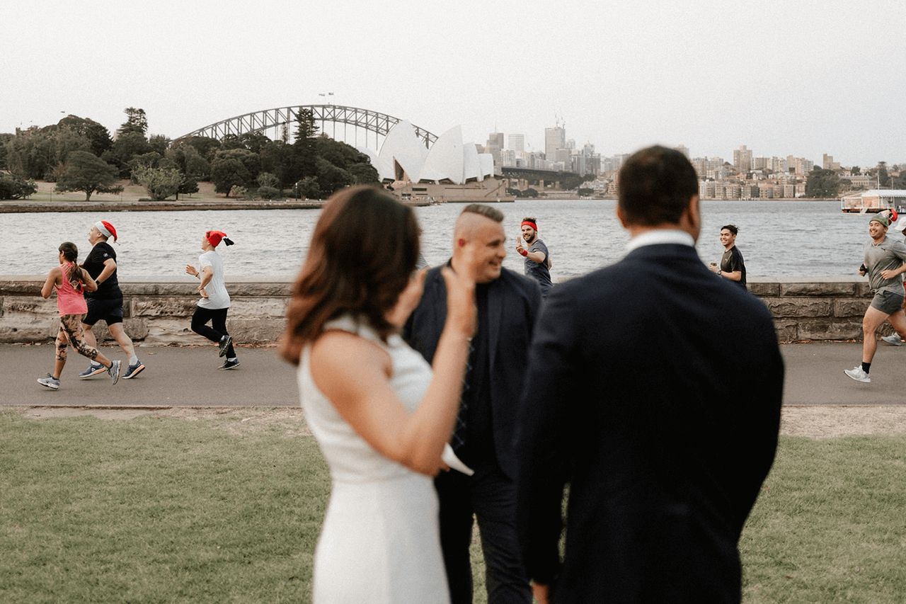 Sydney Botanic Gardens wedding ceremony with the Sydney Opera House in the background as joggers run past the wedding ceremony with Josh Withers marriage celebrant and The Elopement Collective ⌘