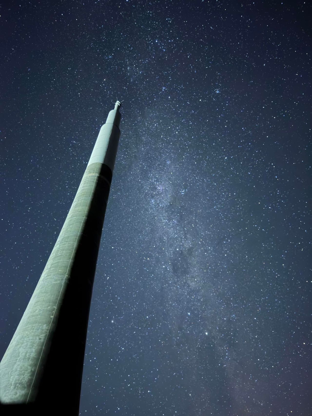 and pink hues over a starry night sky and a dark silhouette.