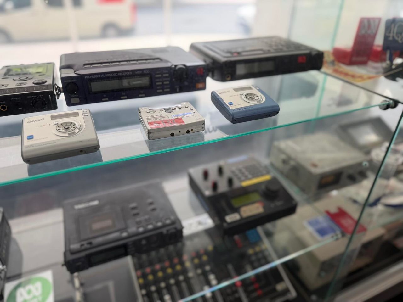 Glass display case with vintage audio recorders and cassette players.