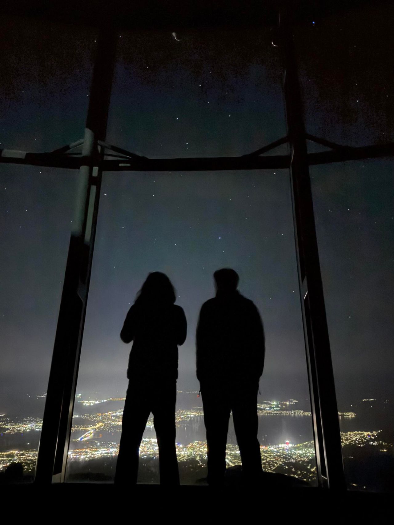 A tall white tower under a starry sky with green and purple auroras.