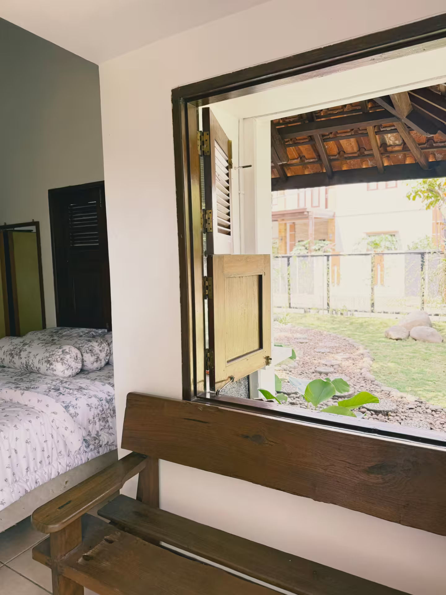 Jendela kamar dirumahdelima dengan pemandangan taman hijau yang tenang
