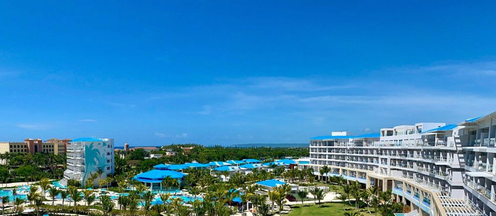 Panoramic view of the facilities, pools, and blue-roofed buildings of the Sensatori Resort Punta Cana