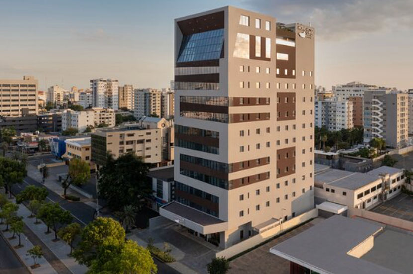 Aerial view of the modern Homewood Suites by Hilton Santo Domingo hotel building in the Dominican Republic during sunset.