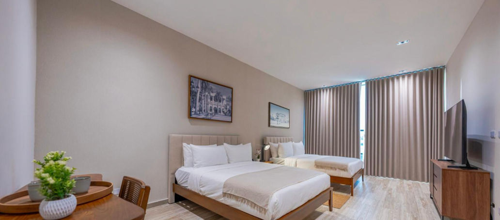 Habitacion moderna y espaciosa en Mauad Hotel Boutique con grandes ventanales, cama doble, sala de estar y una vista panoramica al mar de Santo Domingo