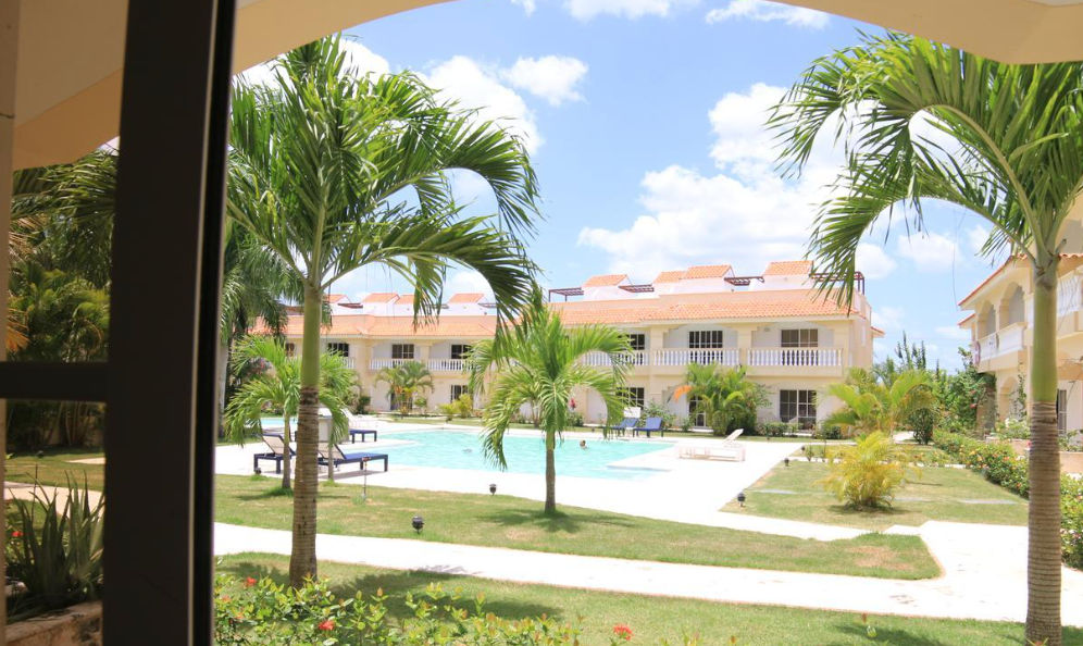 Vista aérea de la piscina y los edificios residenciales amarillos en Residencial Las Palmeras de Willy en Boca Chica