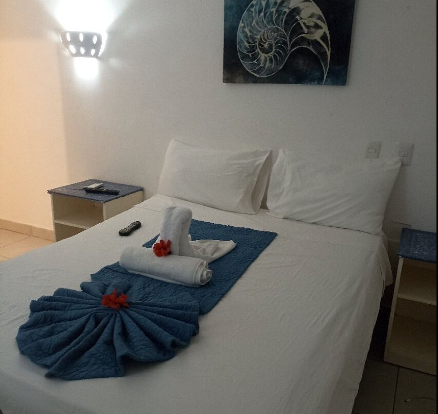 Fachada del Bayahibe Hotel El Pulpo con edificios blancos de dos niveles, toldos azules y estacionamiento