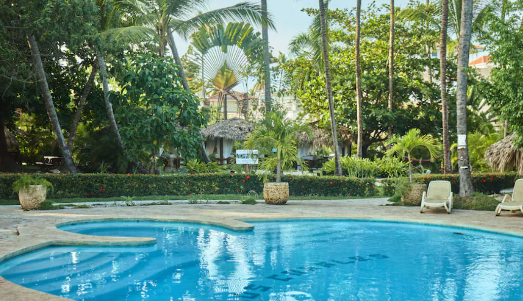 View of the tall palm trees and the facade of the Flor del Mar Condo Hotel in Punta Cana under a sunny sky