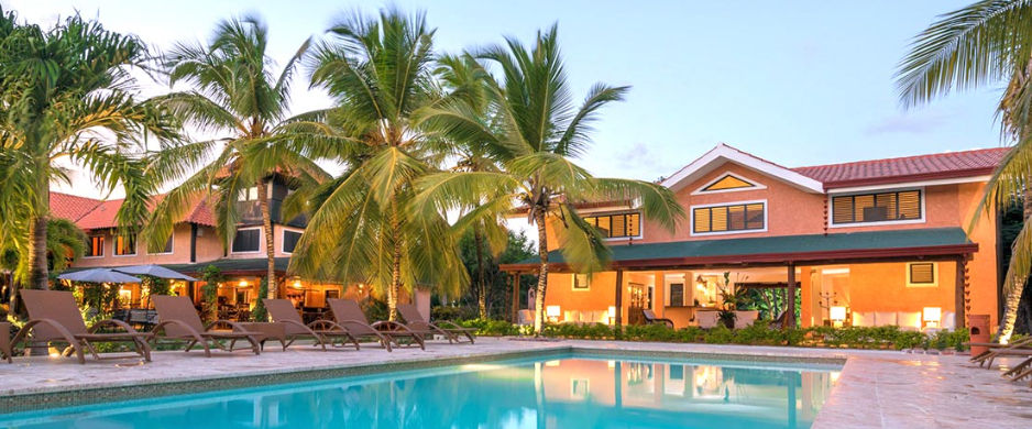 Outdoor swimming pool at Vecchia Caserma hotel surrounded by palm trees and lounge chairs at sunset