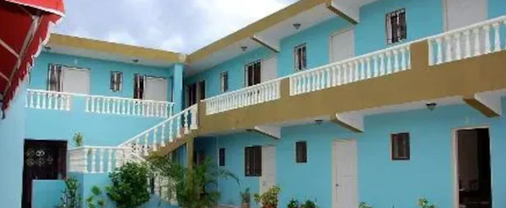 Two-story facade of Hotel Bella Catalina in La Romana featuring turquoise blue walls and white balconies