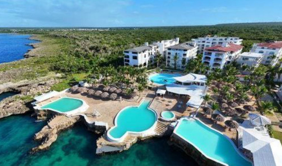 Vista aérea del hotel whala!bayahibe junto al mar, mostrando sus piscinas infinitas, terrazas con palapas y edificios rodeados de vegetación tropical en República Dominicana.