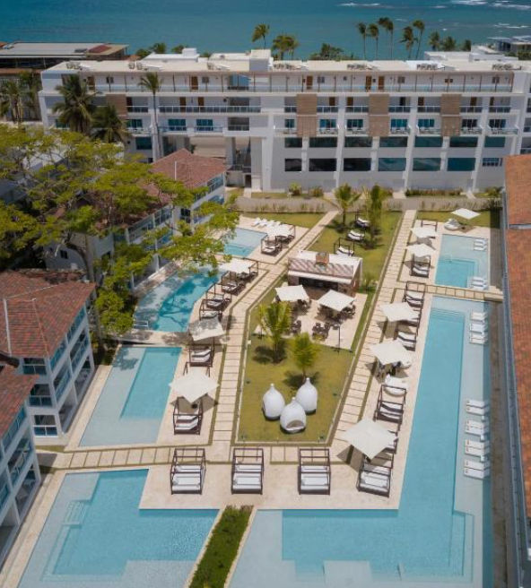 Modern facade of Presidential Suites Lifestyle Cabarete resort beachfront with swimming pool and palm trees