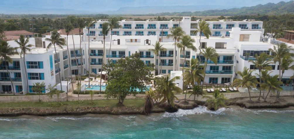 Modern facade of Presidential Suites Lifestyle Cabarete resort beachfront with swimming pool and palm trees