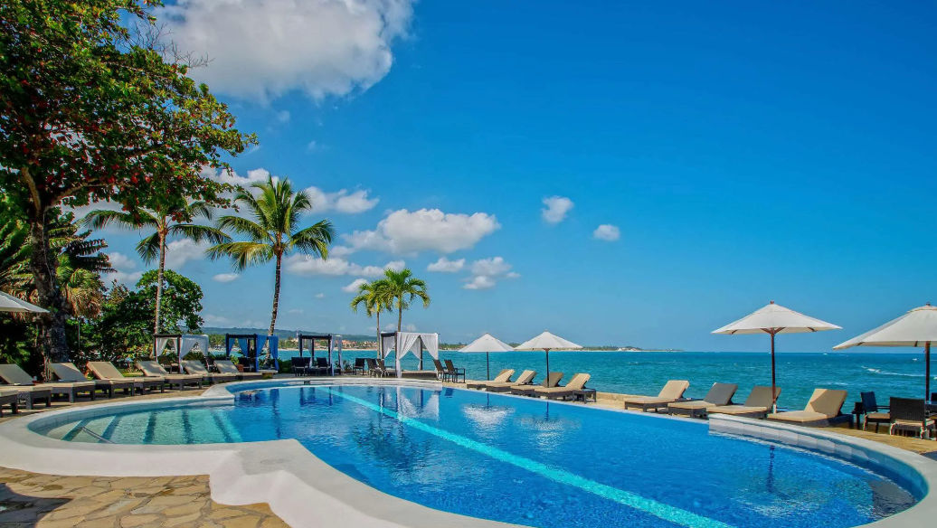 Vista panorámica de las instalaciones de Velero Beach Resort con palmeras, jardines, piscina y el mar de fondo en Cabarete