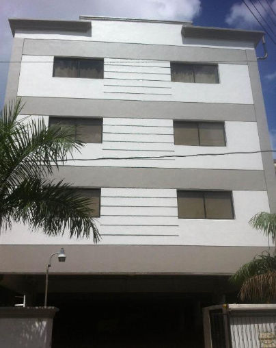 Exterior facade of Micro Hotel Condo Suites in Santo Domingo, a modern three-story building with gray and white stripes.