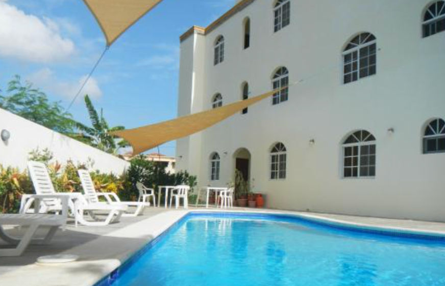 Fachada exterior del Costambar Hotel en Puerto Plata con balcones de arcos blancos y letrero vertical