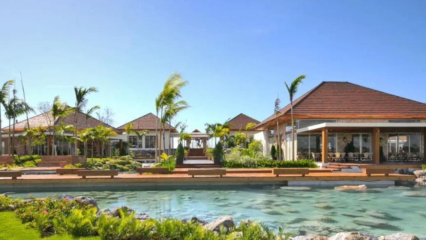 Main entrance and reception area of Los Establos Cap Cana with rustic wooden roofs and tropical garden