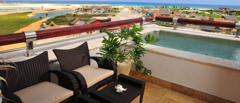 Illuminated main entrance of the luxury hotel Xeliter Golden Bear Lodge in Cap Cana, featuring a circular fountain, limestone arches, and residential villas at sunset.