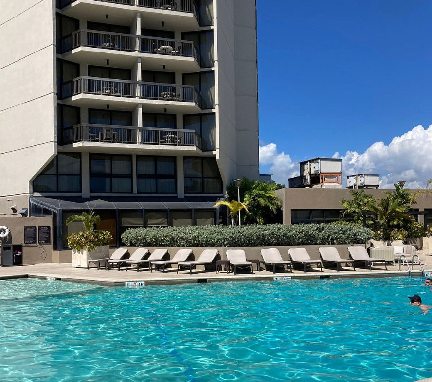 Vista aérea del Sheraton Santo Domingo Hotel con su fachada blanca, piscina exterior, palmeras y el mar Caribe de fondo