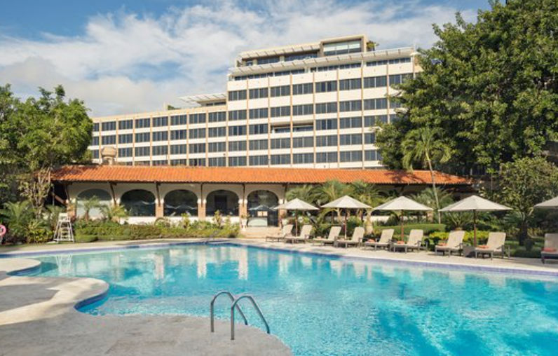 Piscina exterior de El Embajador a Royal Hideaway Hotel con camastros, sombrillas y el edificio principal al fondo en Santo Domingo