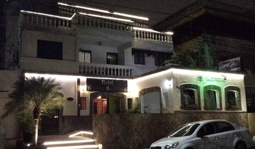Nighttime illuminated facade of Hotel Maison Gautreaux in Gascue, Santo Domingo, showing the classic-style entrance and a car parked in front.