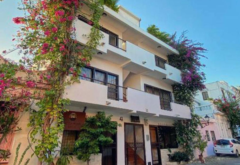 Exterior facade of Casa La Maria in the Colonial Zone of Santo Domingo, showing the boutique-style building entrance with balconies and tropical flowers.