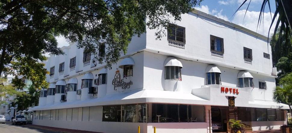 Three story white facade of Hotel La Casona Dorada in Santo Domingo featuring arched windows