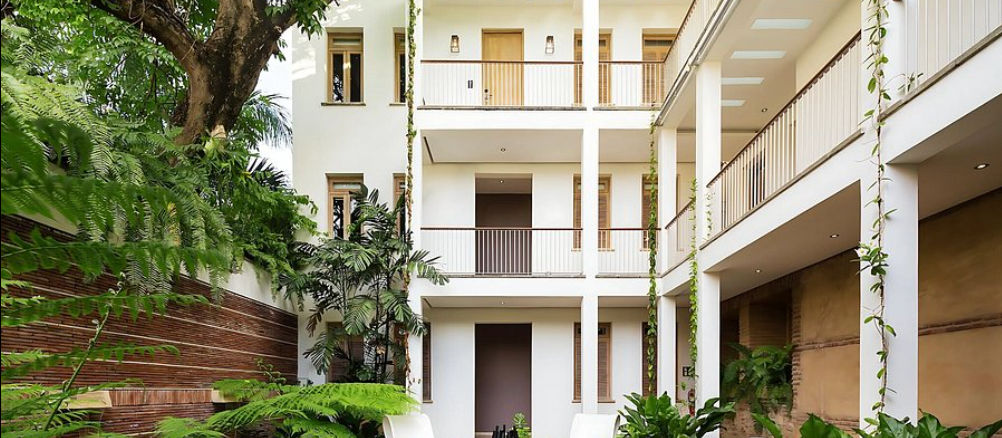 Interior courtyard of the Billini Hotel Historic Luxury featuring white balconies, tropical plants, and colonial architecture